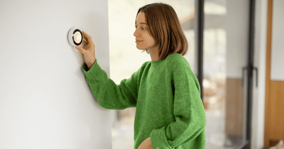 woman turning down thermostat